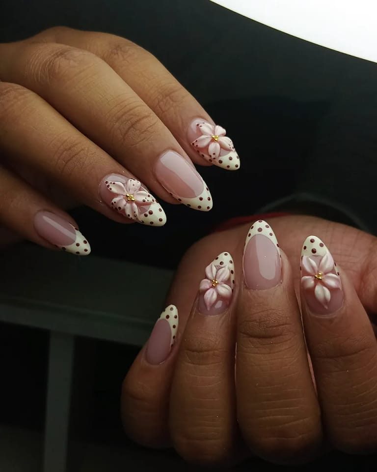 Uñas almendra nude con flores suaves y puntos dorados