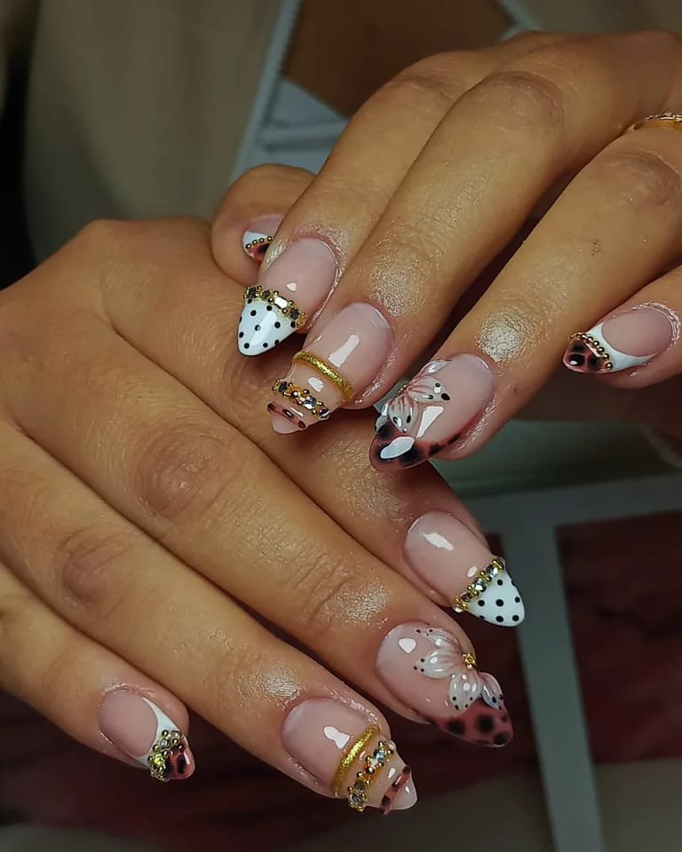 Nail art con lunares y detalles dorados sobre uñas almendra